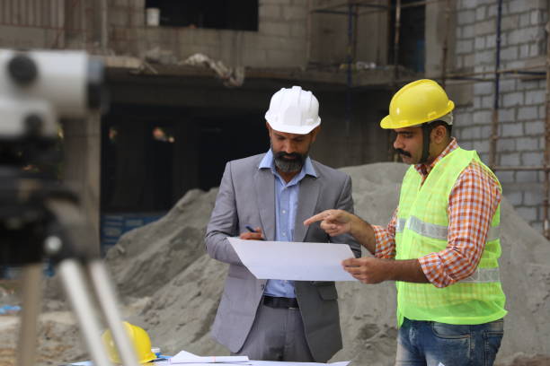 istock Hardworking Indian Site engineer and manager analysing the blueprint and figuring out the work in progress. Reporting the inspector. 1486241469