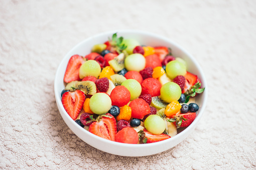 Healthy fruit spring salad. Healthy diet concept. Delicious fresh berries in bowl. Selective focus. Top view. Colourful fruits mixed in homemade salad. Nutrition concept