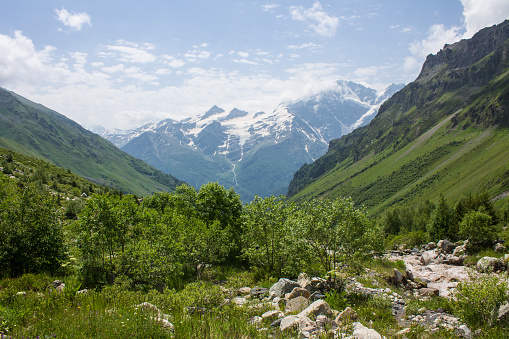 Mountain river Terskol with rocky banks and in a valley from a hill and with green grass in the Elbrus region in the North Caucasus and copy space