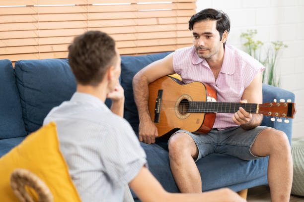 istock gay couple with guitar sitting on sofa. 1486252024