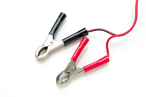 Red and black clip-on connecting and charging cable for 12 Volt battery isolated on white background