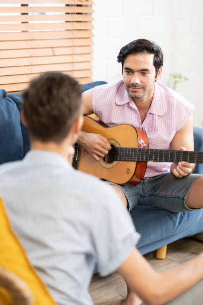 istock gay couple with guitar sitting on sofa. 1486252026