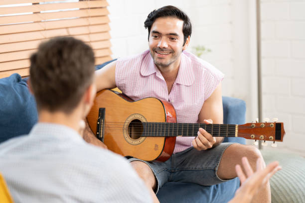 istock gay couple with guitar sitting on sofa. 1486252043