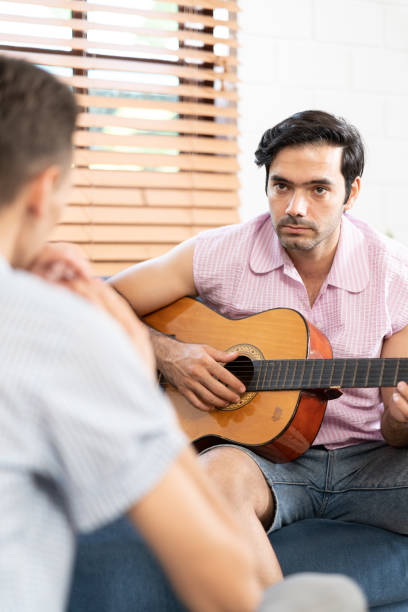 istock gay couple with guitar sitting on sofa. 1486252060