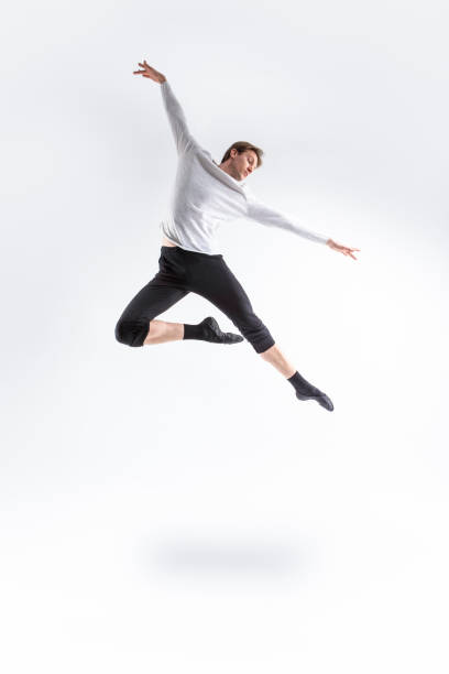 istock One Professional Caucasian Handsome Young Athlete Man Posing in Flying Ballet Pose with Lifted Hands in White Shirt On White. 1486252898