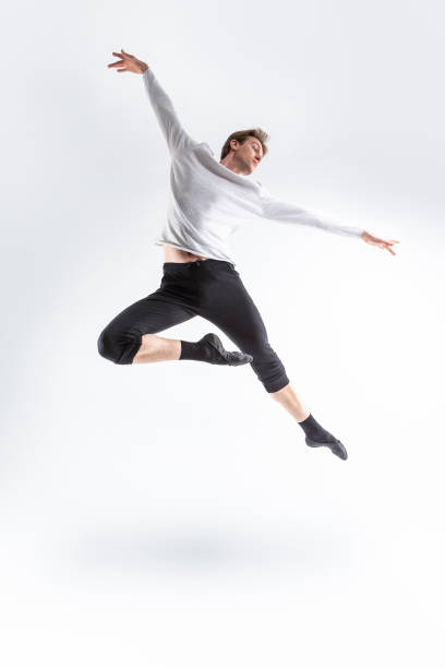 istock One Active Professional Caucasian Handsome Young Athlete Man Posing in Flying Ballet Pose with Lifted Hands in White Shirt On White. 1486252902
