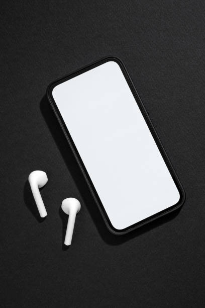 istock Smartphone with blank screen and wireless headphones next to it on dark gray background 1486260728
