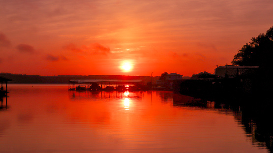 The skies are red and the sun is rising on beautiful Lake Sinclair in Milledgeville, Georgia.