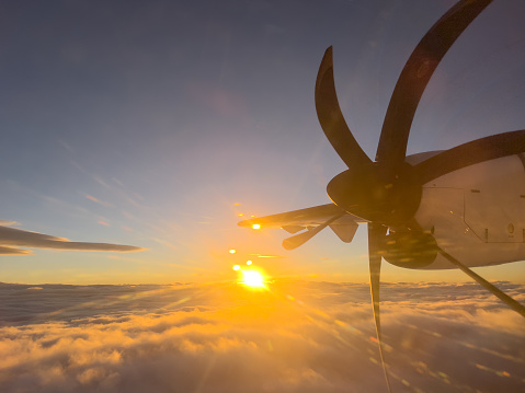 Rotating propeller of an airplane flying in the rays of the setting sun. High quality photo