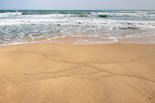 Sandy empty beach, ocean transparent rippled Aegean sea water touch wet sand close up. Greece summer vacation, Cyclades island. Space