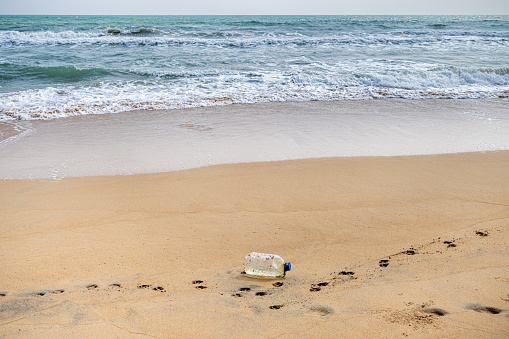 A plastic container for drinking water overgrown with mussels been washed ashore from the Indian Ocean on the tropical beach north of Trincomalee in the Easter Province in Sri Lanka