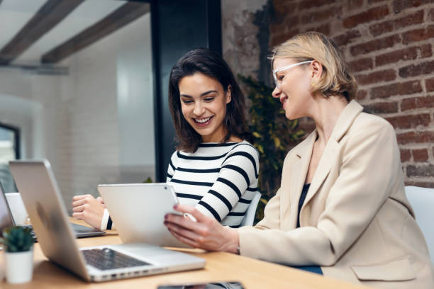 istock Two beautiful designer women working with laptop while choosing materials in digital tablet in the modern office. 1486277768