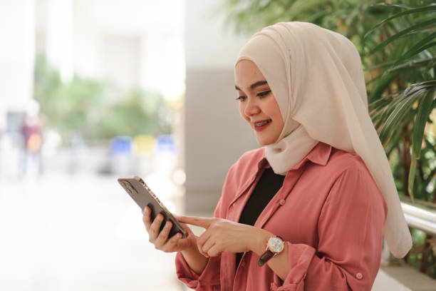 istock A Muslim in white hijab university student seated inside a campus building, holding and using a smartphone. 1486284183
