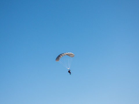 Skydiver with open chute at the blue sky on sunny day