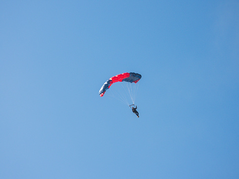 Skydiver with open chute at the blue sky on sunny day