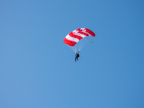 Army Paratrooper with yellow  parachute open and American flag flapping in the wind. Photo taken in non ticket area Miramar Airbase in San Diego California USA on September 23, 2022.