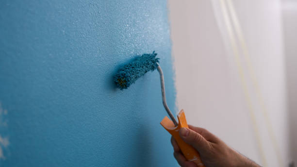 istock Male decorator painting wall in blue color 1486291813