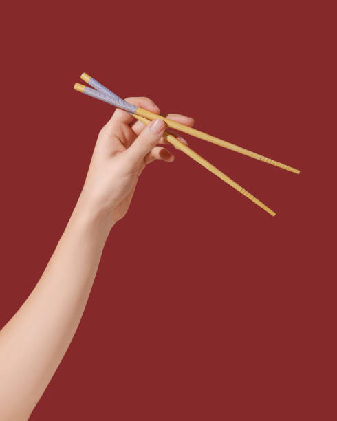 istock Hand holding wooden chopsticks on red background 1486297906