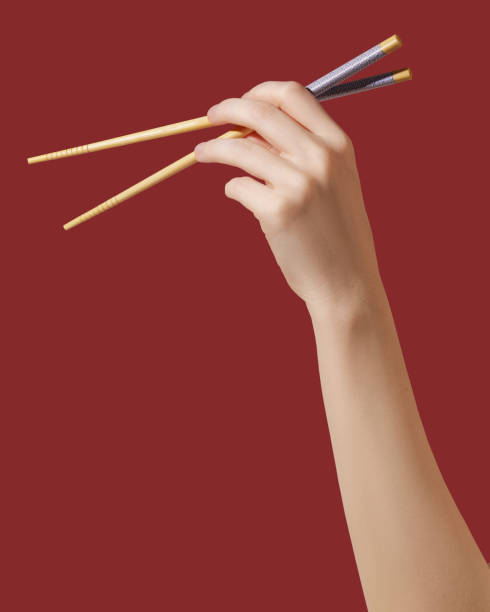 Hand holding wooden chopsticks on red background stock photo