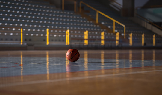 Basketball ball on wooden indoor court.