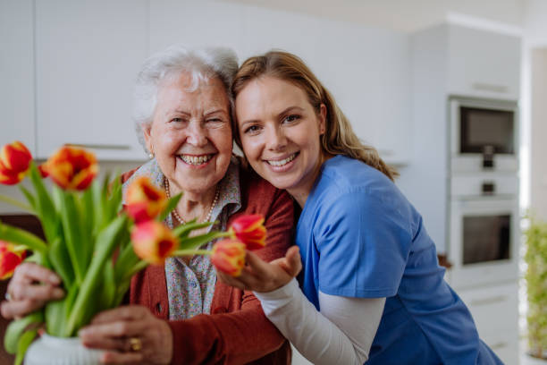 istock Senior woman and nurse with tulip bouquet. 1486314708