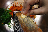 Closeup of an asian woman hand grating garlic with a metal grater