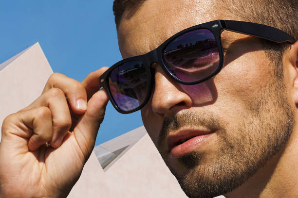 Unshaven man in sunglasses on the background of white architecture, eyewear advertising. Unshaven man in sunglasses on the background of white architecture, sunglasses advertisement. arabian sunglasses stock pictures, royalty-free photos & images