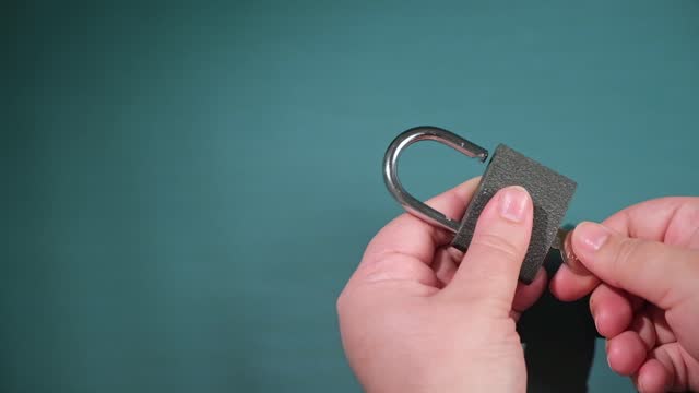 hand opens and closes the padlock with a key on a turquoise background.