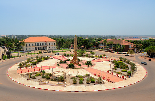 Bissau, Guinea-Bissau: Heroes of the Fatherland Square, a pearl of Portuguese colonial urban planning, originally called Empire Square - the central pavement display's the Portuguese Cross of Christ - the main building is now the Presidential Palace, it was built for the Governor, to the right is the PAIGC party headquarters, originally the building of the Commercial, Industrial and Agricultural Association - the central column by architect Ponce de Castro was dedicated to the 'effort of the race', following independence a star was added and it was re-dedicated to the heroes of independence.