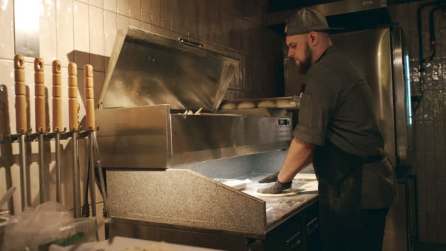 Male Chef Pounding Dough for Pizza in Restaurant Kitchen