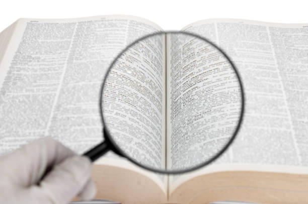 Magnifying glass in hand and dictionary page close up