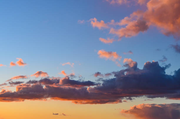 istock A bright yellow and orange sun set with the setting sun reflecting on the surrounding clouds reflecting purples and oranges against a crisp blue sky 1486352376
