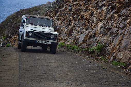Santa Catalina, Spain - 24th October, 2014: Land Rover Defender driving on a road next to the sea. This vehicle is used to get in extremely hard areas.