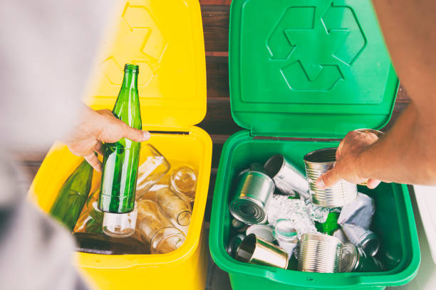 istock Man throwing the glass bottle andtin can into differennt dustbins for sorting trash 1486356168