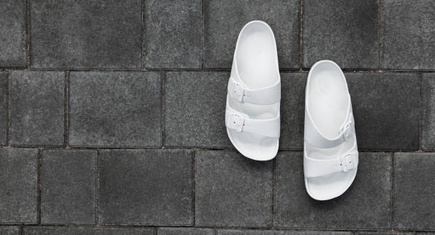 istock Pair of white flip flops on  paving slabs 1486357878