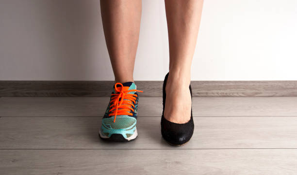 Two different types of shoes on the woman's foots stock photo