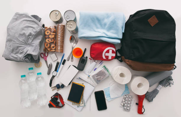 istock Emergency backpack equipment organized on the table. Documents, water,food, first aid kit and another items needed to survive. 1486359077