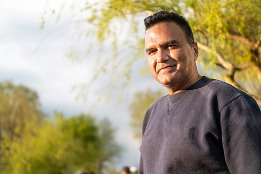 A happy Hispanic man with a calm pine tree background