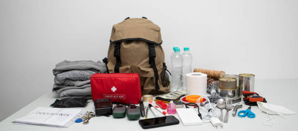 istock Emergency backpack equipment organized on the table. Documents, water,food, first aid kit and another items needed to survive. 1486359218