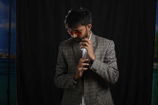 Portrait of happy corporate dressed up person in suit and wearing specs portraying different moods. Low key shoot of bearded office man well suited. Black background.