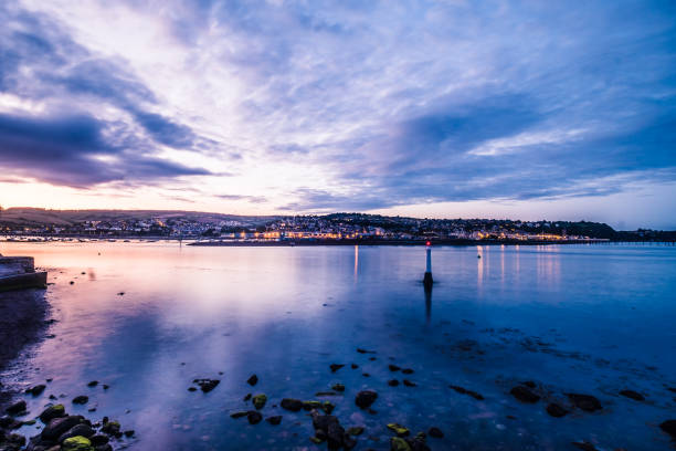 The city lights of Teignmouth at night from the shore of the Ness in Shaldon in long exposure.