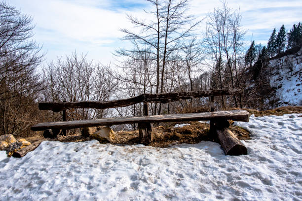 abandoned and lonely wooden bench with snow among the alpine peaks in Campogrosso Vicenza Veneto Italy