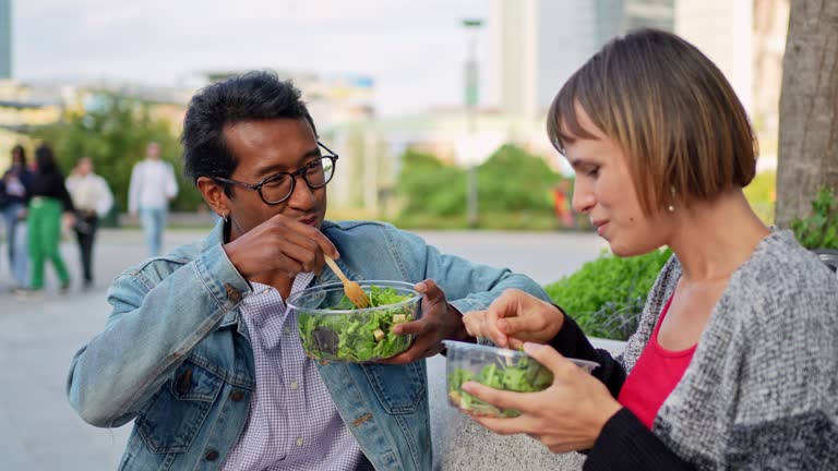 Young couple eating salads and talking outdoors