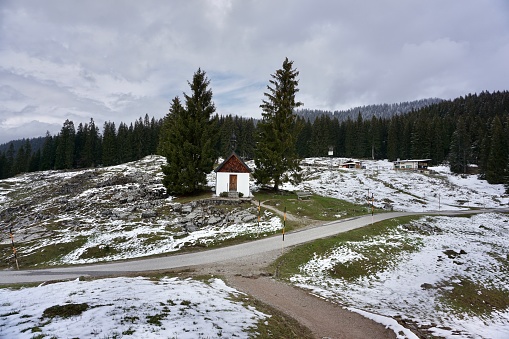 A walking path in the Alps leading to the cross with Jesus. Religious walk. A walk in Bavaria in early spring. The last snow on the hill. The path leading to the chapel.