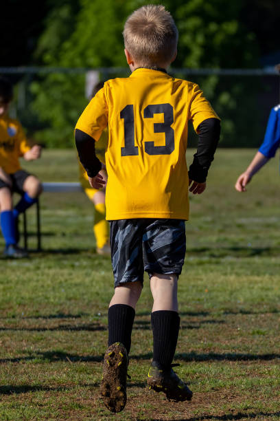 młody chłopiec grający w drużynową piłkę nożną w żółtym mundurze - sports uniform blue team event sports activity zdjęcia i obrazy z banku zdjęć