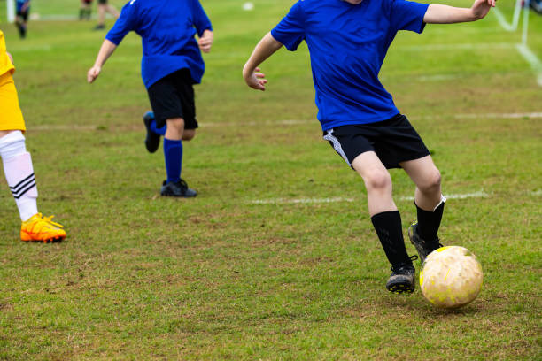 młody chłopiec grający w drużynową piłkę nożną w niebieskim mundurze - sports uniform blue team event sports activity zdjęcia i obrazy z banku zdjęć