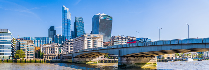 London Bridge overlooked by the futuristic towers of the City of London financial district skyscrapers along the River Thames in the heart of the UK’s vibrant capital city.