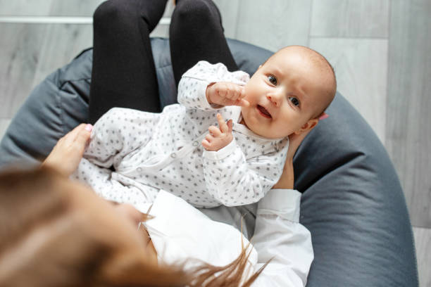 la mère s’occupe du nouveau-né à la maison. maman tient sa petite fille de deux mois dans ses bras. - patient male nurse nurse hospital photos et images de collection