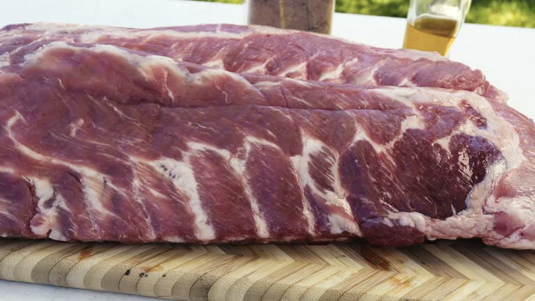 Panning Shot Slow Motion of Barbecue Pork Spare Ribs Being Prepped on a Rustic Cutting Board to Be Slow Smoked on an Old Fashioned Meat Smoker