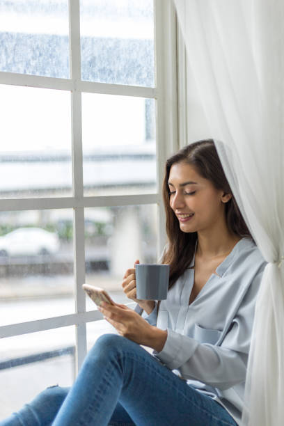 istock Content Creator Enjoying Coffee and Smartphone by the Window 1486412319